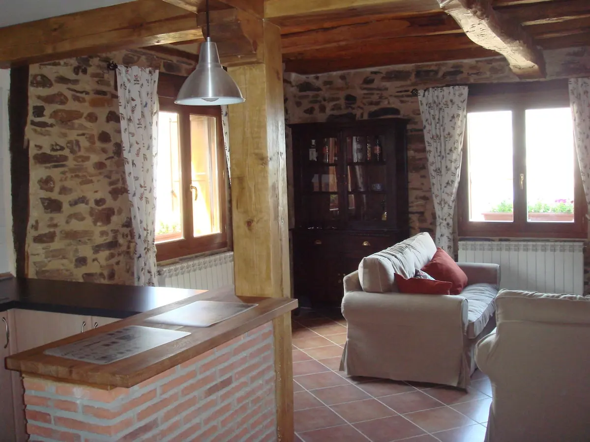Salón con sofás, paredes de piedra y ventanas de madera